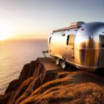 Airstream travel trailer parked on a cliff overlooking the Pacific Ocean at sunset.