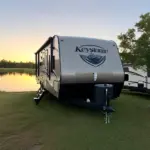 Keystone Hideout parked at a campsite overlooking a lake.