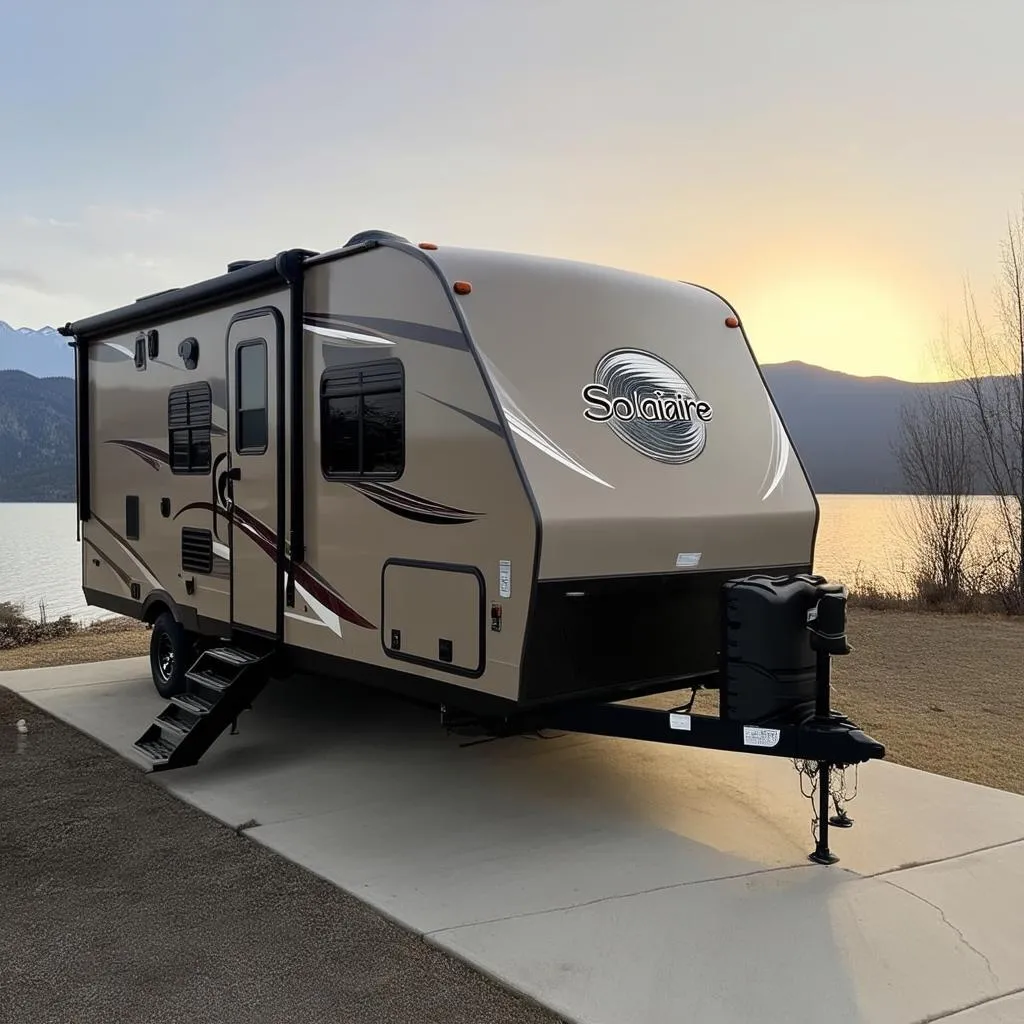 Modern Palomino Solaire travel trailer parked at a scenic campsite overlooking a mountain lake.