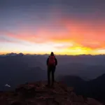 A well-traveled person looking out over a mountainous landscape at sunset.