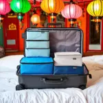 Packing cubes neatly arranged in a suitcase, with a backdrop of colorful lanterns in Hoi An.