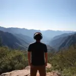 Person wearing headphones, looking out at a mountain range