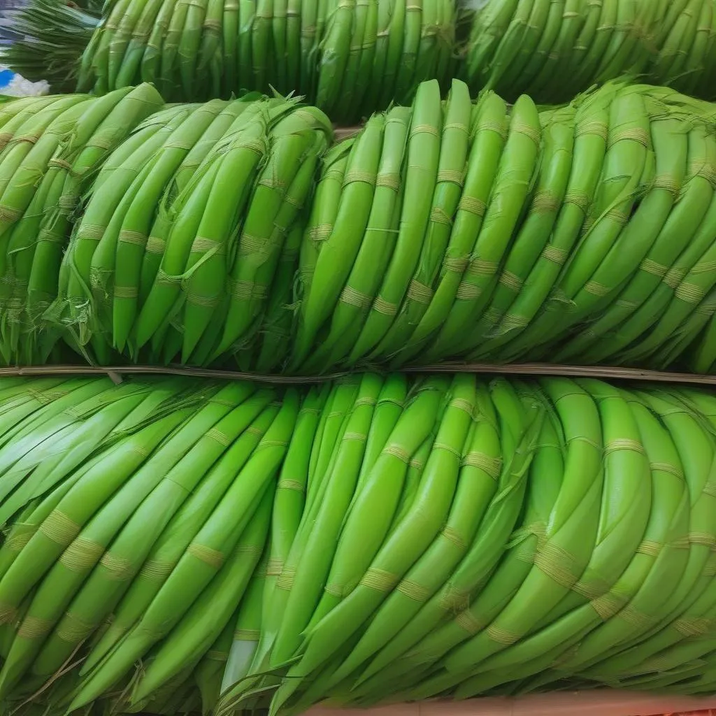 Stacks of vibrant green pandan leaves neatly arranged for sale at a bustling Asian market.