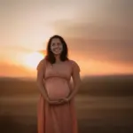 Pregnant woman smiling at sunset