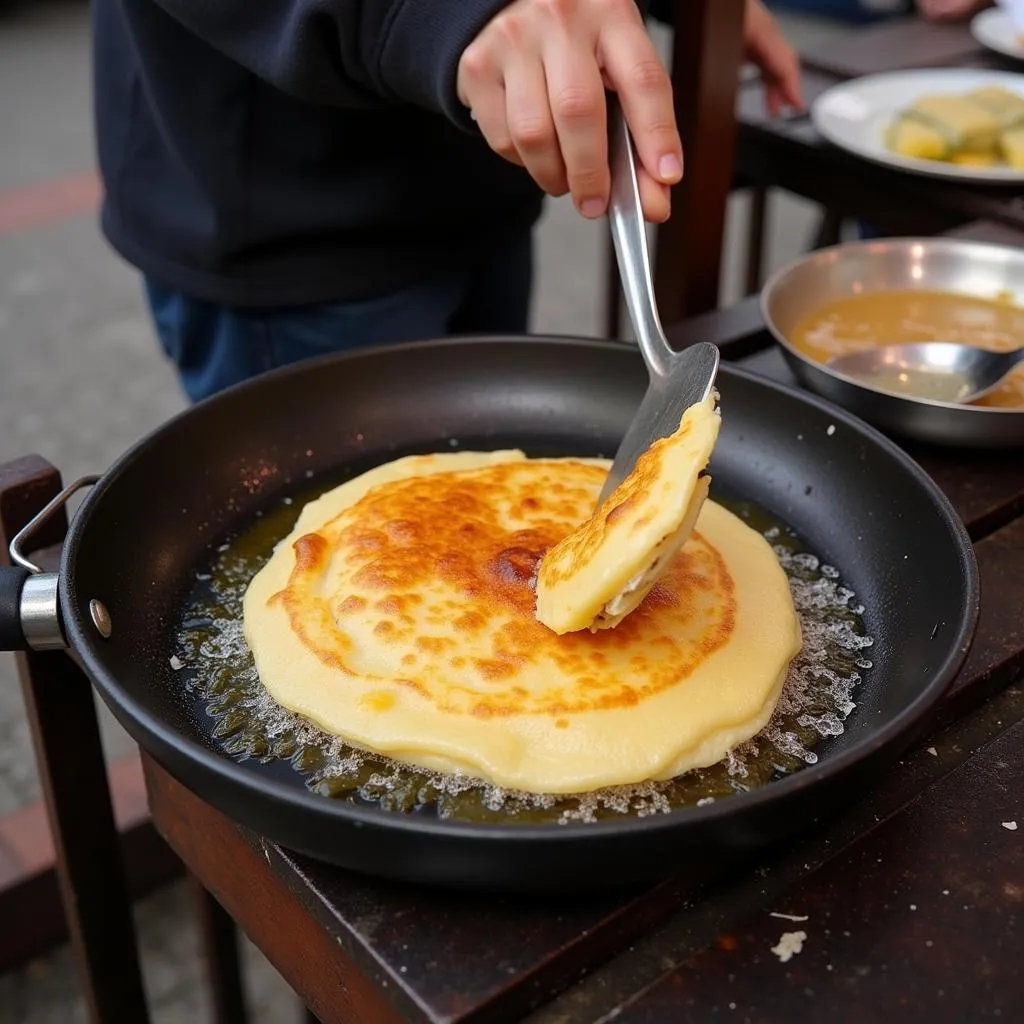 Banh Xeo: A crispy crepe being cooked on a street stall in Soc Trang