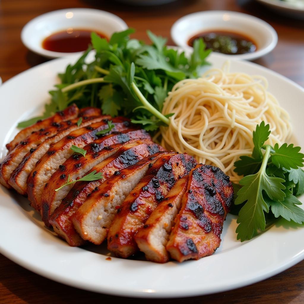 Close-up shot of a plate of Bun Cha, highlighting the grilled pork, vermicelli noodles, fresh herbs, and dipping sauce.