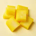 A close-up of bright yellow slices of takuan, showcasing its texture and vibrant color.