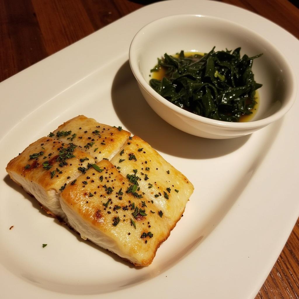 A plate of grilled fish served alongside a bowl of seaweed soup.